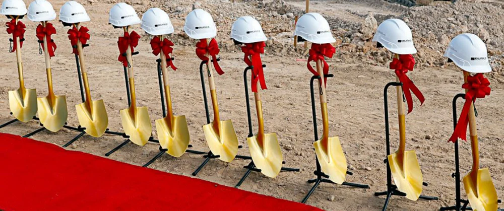 Gold ceremonial shovels with red bows and white hard hats